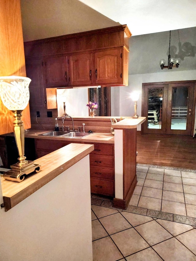 kitchen with kitchen peninsula, light tile patterned floors, butcher block counters, and sink