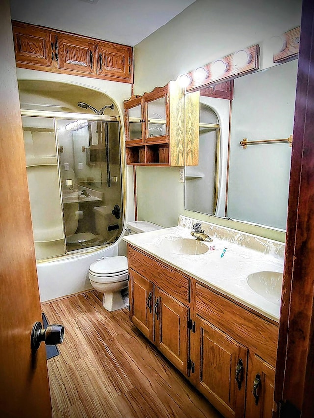 full bathroom with toilet, vanity, bath / shower combo with glass door, and wood-type flooring