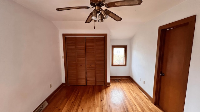 unfurnished bedroom with a closet, ceiling fan, hardwood / wood-style floors, and vaulted ceiling