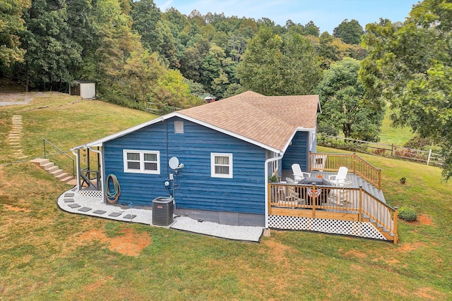 rear view of property featuring a lawn, a wooden deck, a storage shed, and central air condition unit