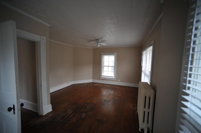 empty room featuring dark hardwood / wood-style flooring, ceiling fan, radiator heating unit, and ornamental molding