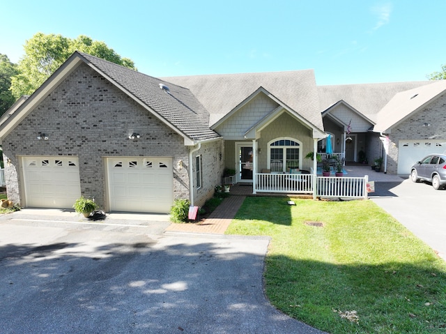 view of front of home featuring a porch, a garage, and a front yard