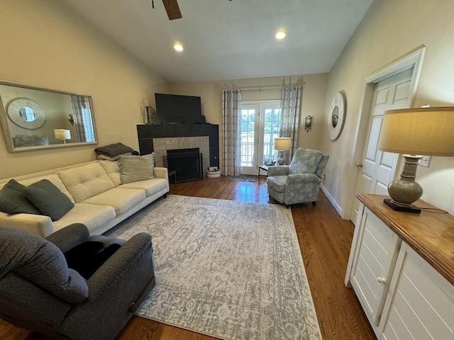 living room with a tile fireplace, ceiling fan, and dark hardwood / wood-style flooring