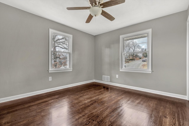 empty room with dark hardwood / wood-style floors, a healthy amount of sunlight, and ceiling fan