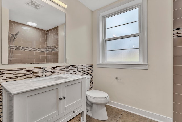 bathroom with a wealth of natural light, tile patterned flooring, vanity, and toilet