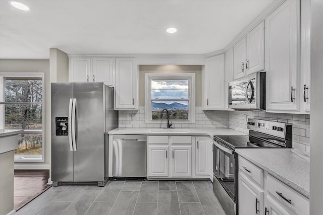 kitchen featuring white cabinets, sink, light stone countertops, and stainless steel appliances