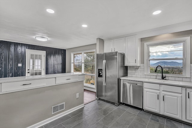 kitchen with decorative backsplash, light stone counters, stainless steel appliances, sink, and white cabinetry