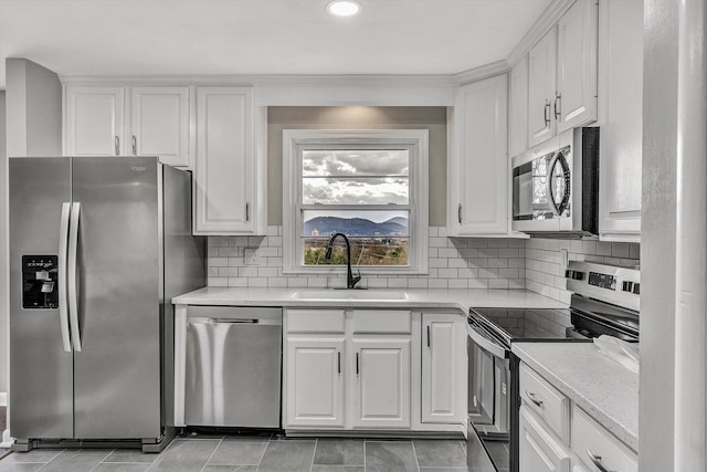 kitchen featuring light stone countertops, sink, decorative backsplash, white cabinets, and appliances with stainless steel finishes