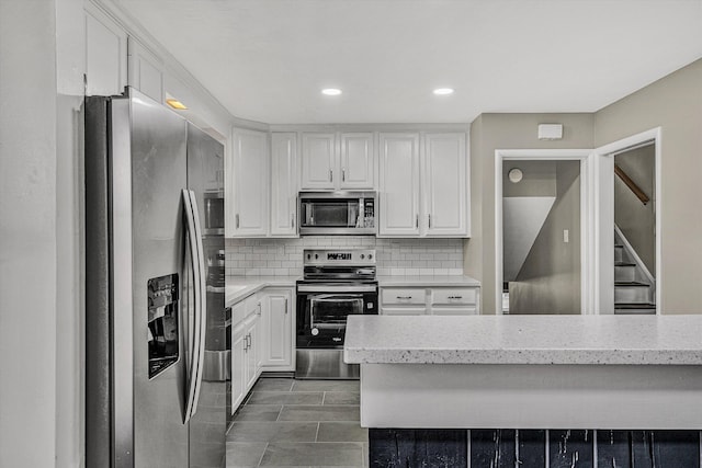 kitchen with backsplash, white cabinets, and stainless steel appliances