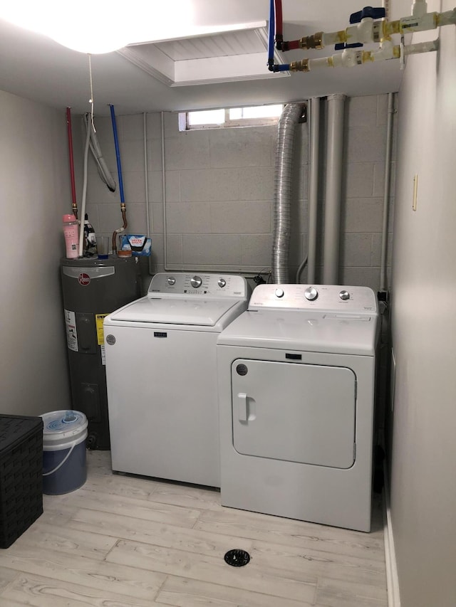 laundry room with light hardwood / wood-style floors, washing machine and dryer, and water heater