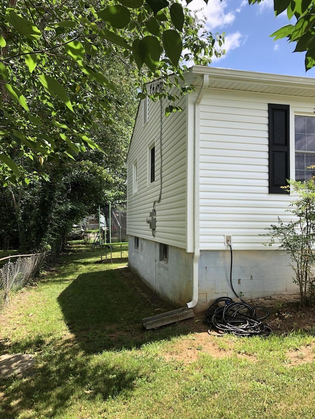 view of side of home featuring a lawn and a trampoline