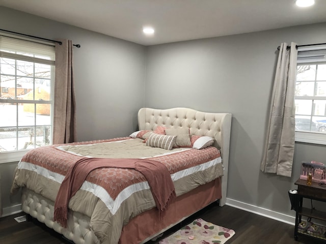 bedroom with dark hardwood / wood-style flooring and multiple windows