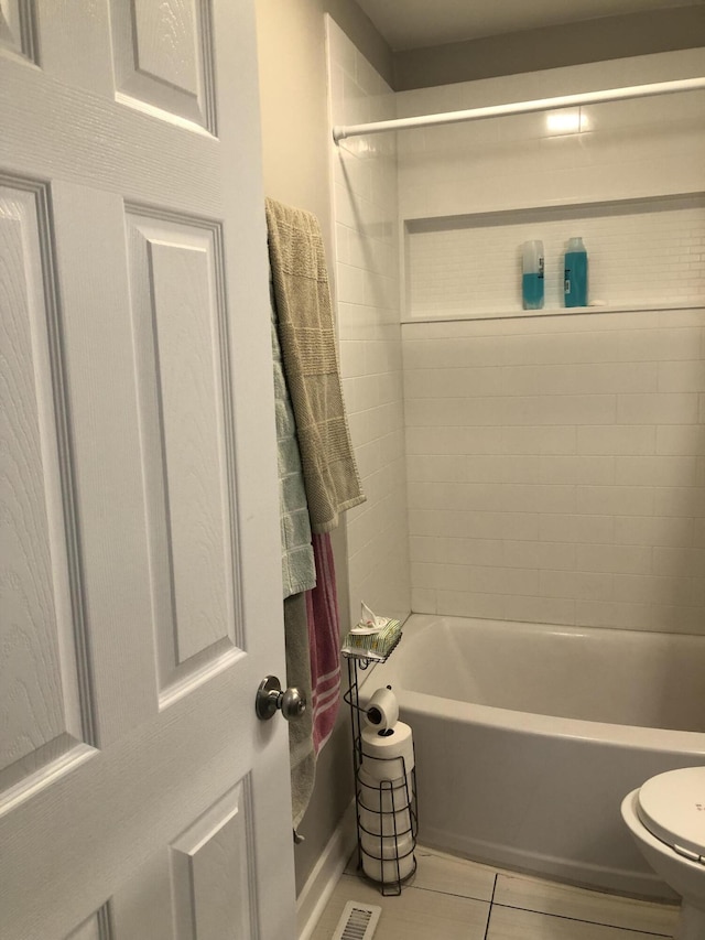 bathroom with tile patterned flooring, toilet, and tiled shower / bath