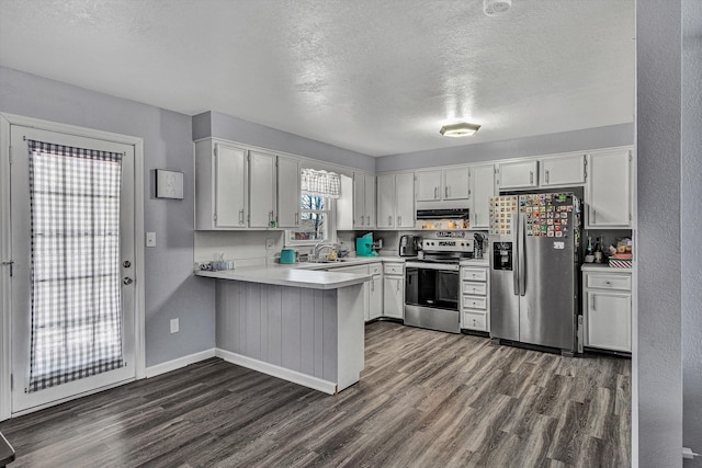 kitchen with white cabinetry, kitchen peninsula, appliances with stainless steel finishes, dark wood-type flooring, and a textured ceiling