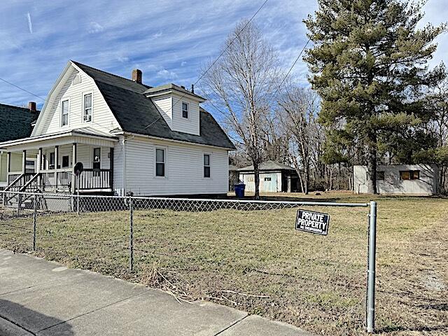 view of side of home featuring covered porch and a lawn