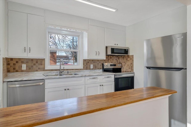 kitchen with butcher block counters, sink, white cabinets, and appliances with stainless steel finishes