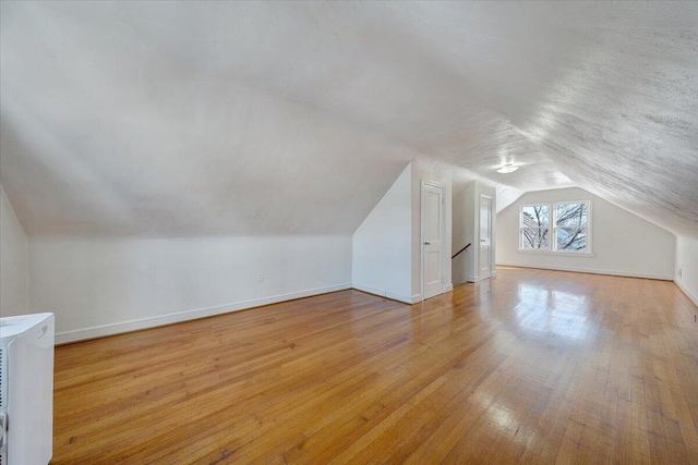 additional living space featuring light hardwood / wood-style flooring and vaulted ceiling