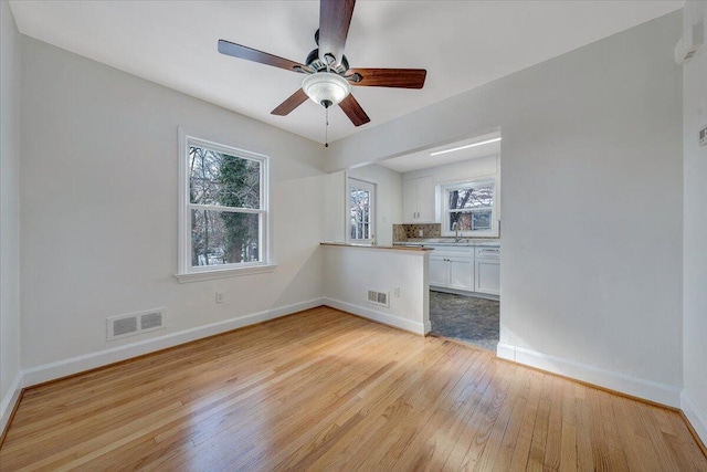 unfurnished room featuring ceiling fan, light hardwood / wood-style floors, and sink