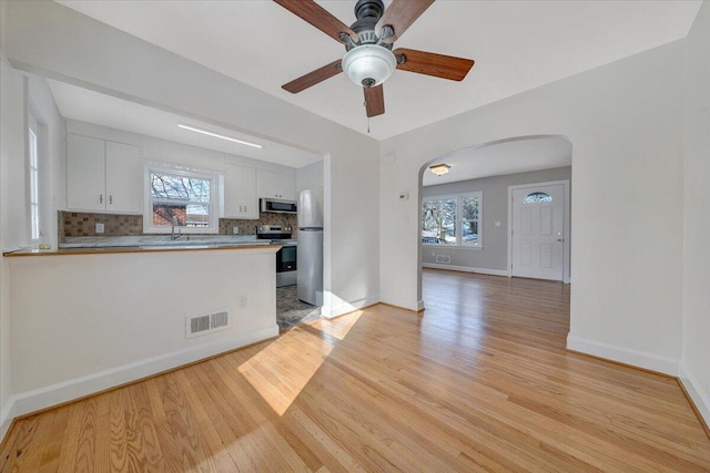 kitchen with decorative backsplash, white cabinetry, plenty of natural light, and appliances with stainless steel finishes