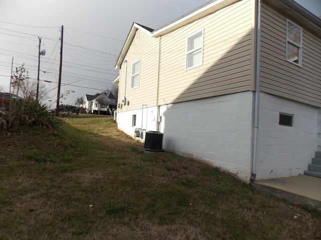 view of side of property featuring central air condition unit and a lawn