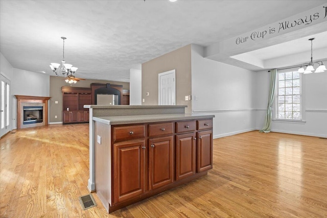 kitchen featuring ceiling fan with notable chandelier, hanging light fixtures, and light wood-type flooring