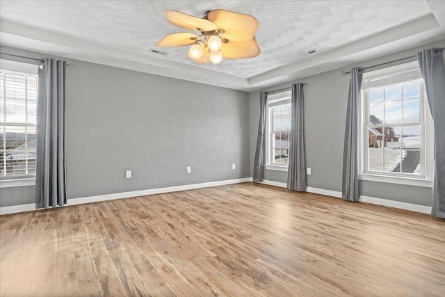 spare room featuring light hardwood / wood-style flooring, a raised ceiling, and ceiling fan