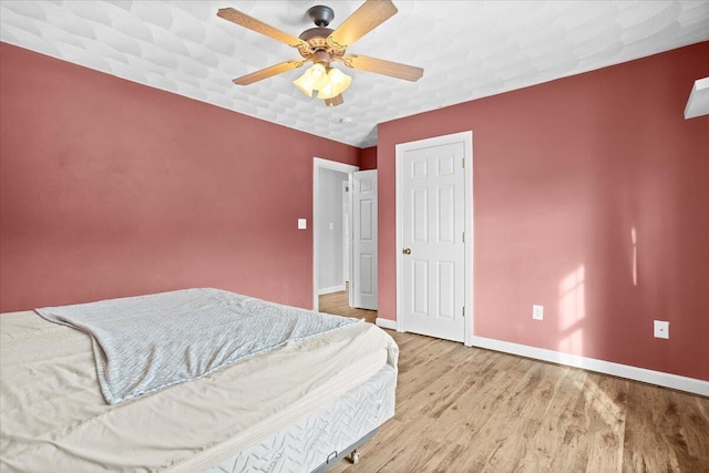 bedroom with a textured ceiling, ceiling fan, and light hardwood / wood-style flooring