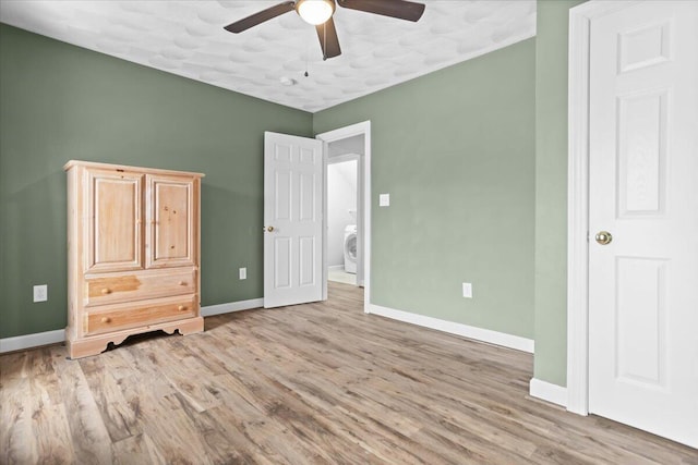 unfurnished bedroom with washer / dryer, ceiling fan, and light wood-type flooring