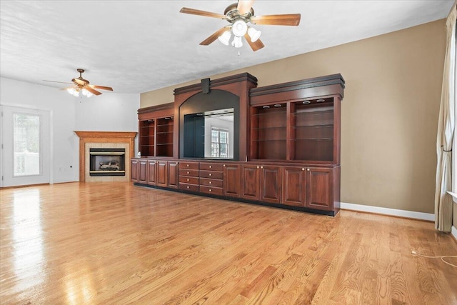 unfurnished living room featuring light hardwood / wood-style floors, a tile fireplace, and ceiling fan