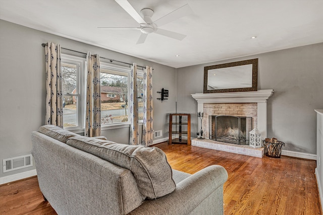 living room featuring ceiling fan, a fireplace, and hardwood / wood-style floors