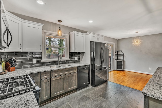 kitchen with hanging light fixtures, black appliances, sink, and white cabinets