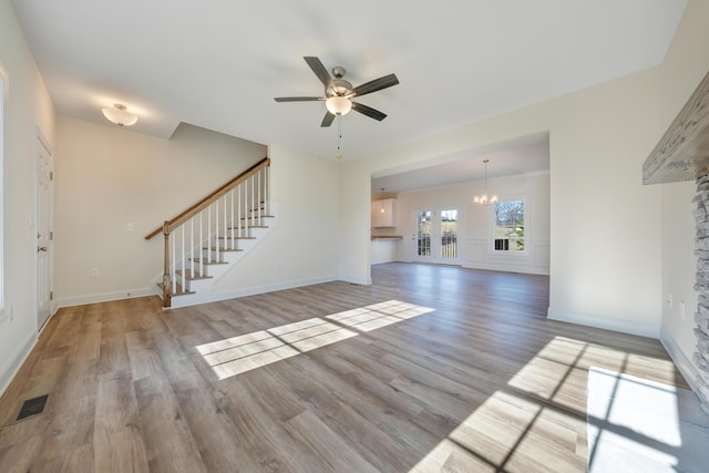 unfurnished living room featuring ceiling fan with notable chandelier and light wood-type flooring