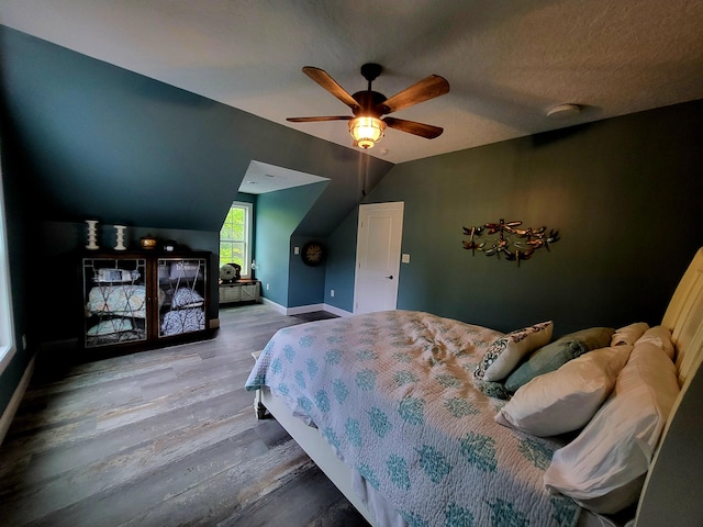 bedroom featuring hardwood / wood-style floors, a textured ceiling, ceiling fan, and lofted ceiling