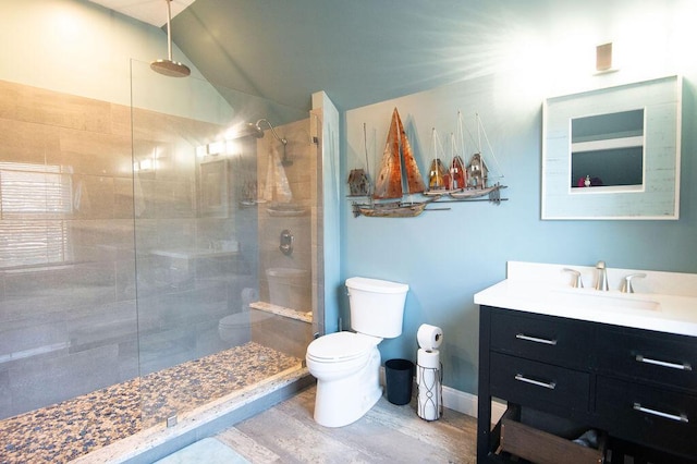 bathroom featuring a tile shower, vaulted ceiling, toilet, vanity, and hardwood / wood-style flooring