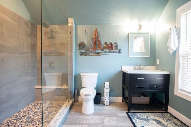 bathroom featuring tiled shower, vanity, and toilet