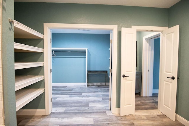 walk in closet with light hardwood / wood-style floors