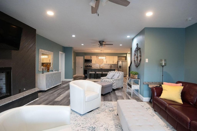 living room with a fireplace, hardwood / wood-style flooring, and ceiling fan