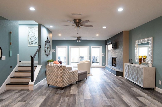 living room featuring a premium fireplace, ceiling fan, and dark hardwood / wood-style floors