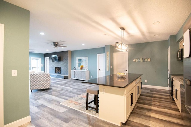 kitchen with white cabinetry, ceiling fan, dark hardwood / wood-style flooring, decorative light fixtures, and a kitchen island