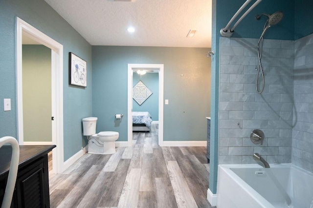 full bathroom with a textured ceiling, vanity, hardwood / wood-style floors, toilet, and tiled shower / bath