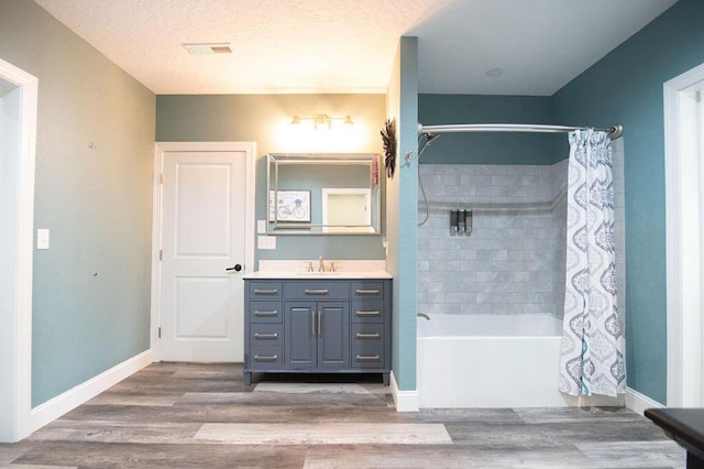 bathroom featuring vanity, shower / bathtub combination with curtain, wood-type flooring, and a textured ceiling