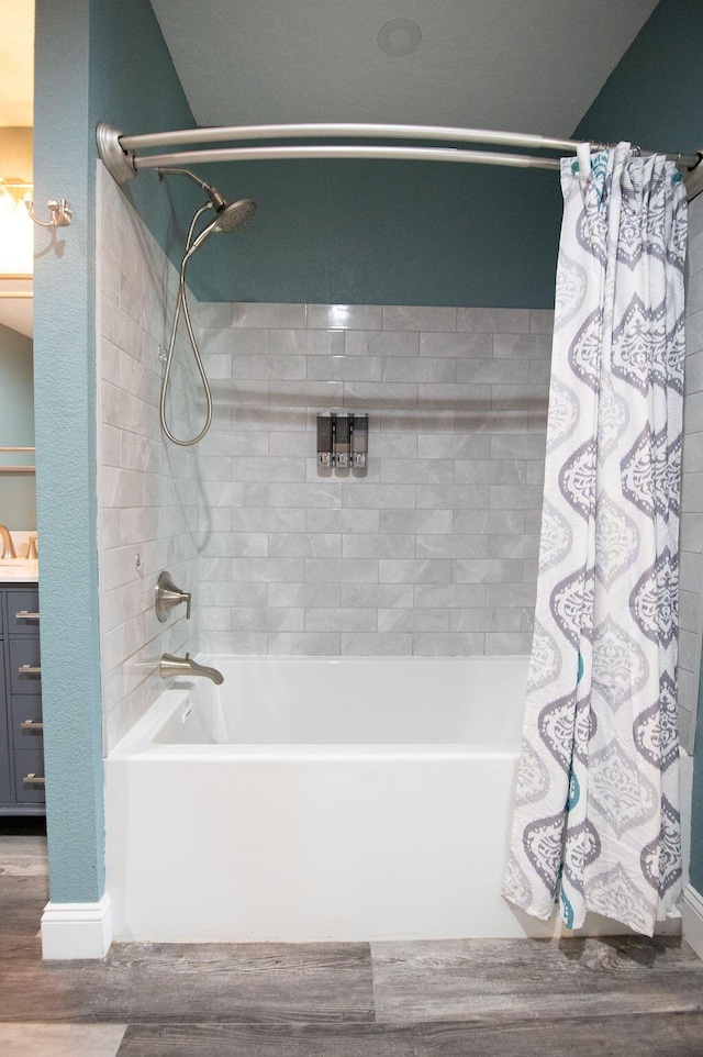 bathroom with hardwood / wood-style floors, vanity, and shower / bathtub combination with curtain