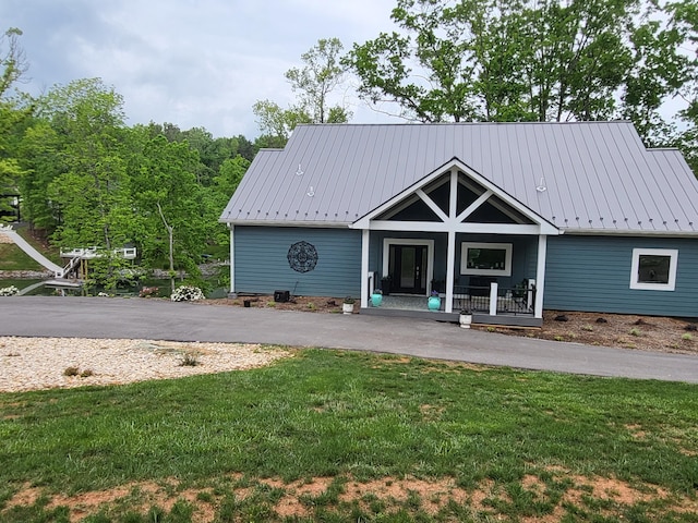 rear view of property featuring a lawn and covered porch