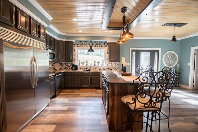 kitchen with pendant lighting, a kitchen bar, wooden ceiling, and appliances with stainless steel finishes