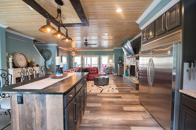 kitchen with ceiling fan, a stone fireplace, hardwood / wood-style floors, high end fridge, and a kitchen island