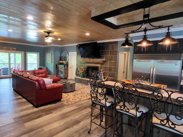 interior space with ceiling fan, wooden ceiling, light hardwood / wood-style flooring, a fireplace, and ornamental molding