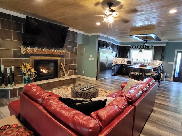 living room featuring ceiling fan, a fireplace, hardwood / wood-style floors, and ornamental molding