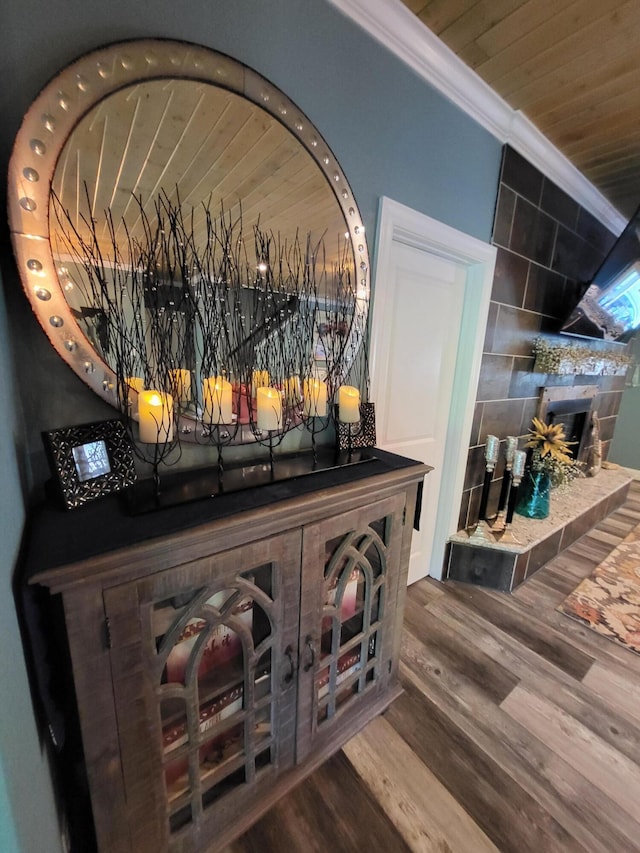 room details with a tiled fireplace, crown molding, and hardwood / wood-style flooring