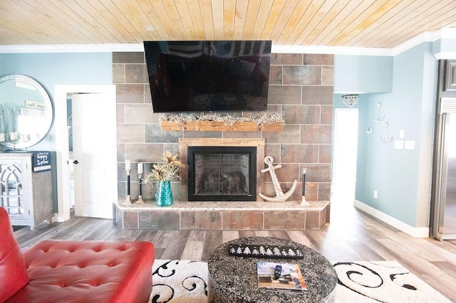 living room with wood ceiling, a tiled fireplace, wood-type flooring, and ornamental molding