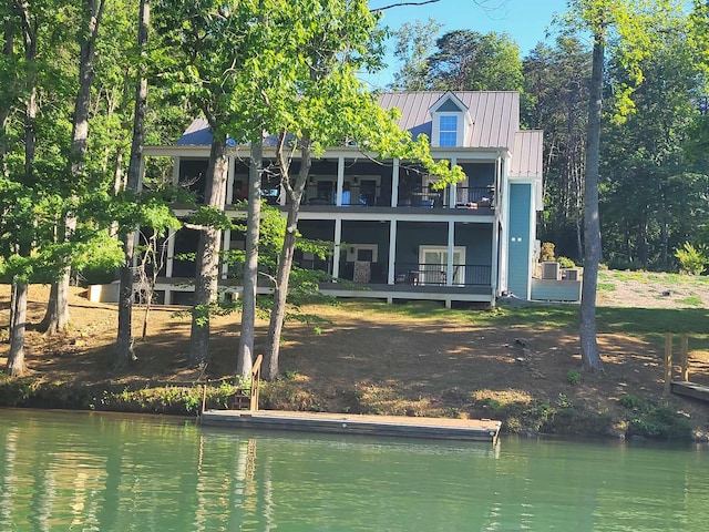 back of property with a balcony and a water view